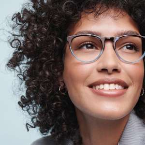 woman with curly brown hair smiling wearing glasses