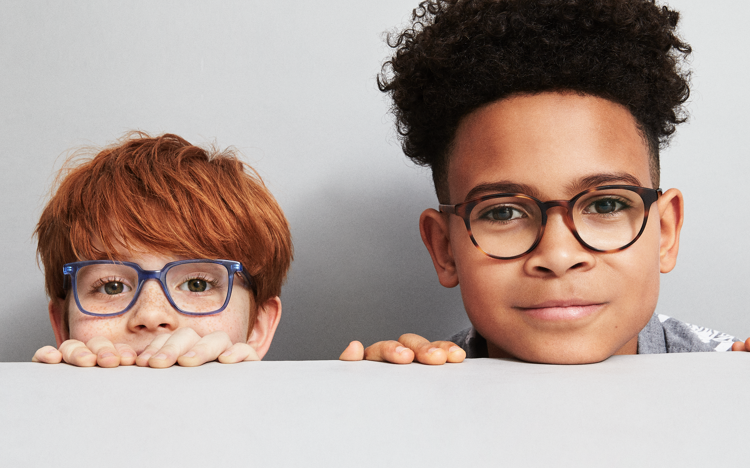 two boys peeking heads above tabletop